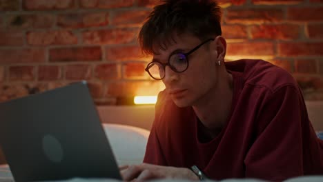 young man working on laptop in bed at night