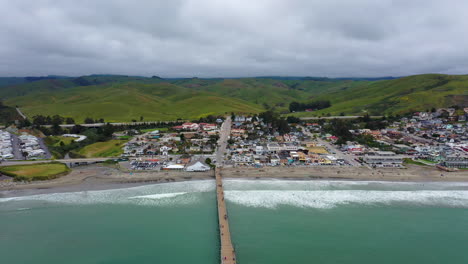 look back drone shot of the californian coast line with a jetty in the center of the shot