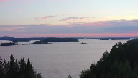 Aerial-drone-shot-of-revealing-lake-scenery-from-a-forest-by-sunset-golden-hour