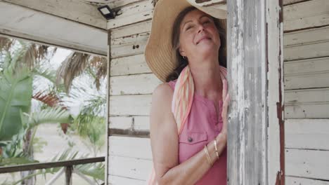 Glückliche-ältere-Kaukasische-Frau,-Die-Sich-In-Zeitlupe-Auf-Der-Veranda-Eines-Hölzernen-Strandhauses-Entspannt