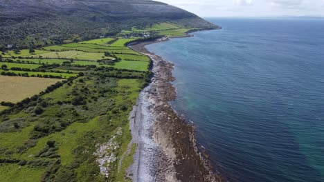 West-of-Ireland,-the-deep-blue-sea-meets-the-green-land-on-the-edge-of-the-Burren