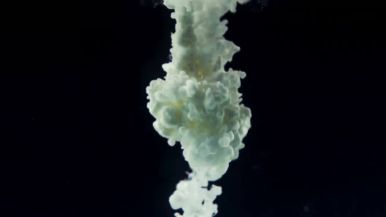 зеленые чернила кружатся в воде против черного