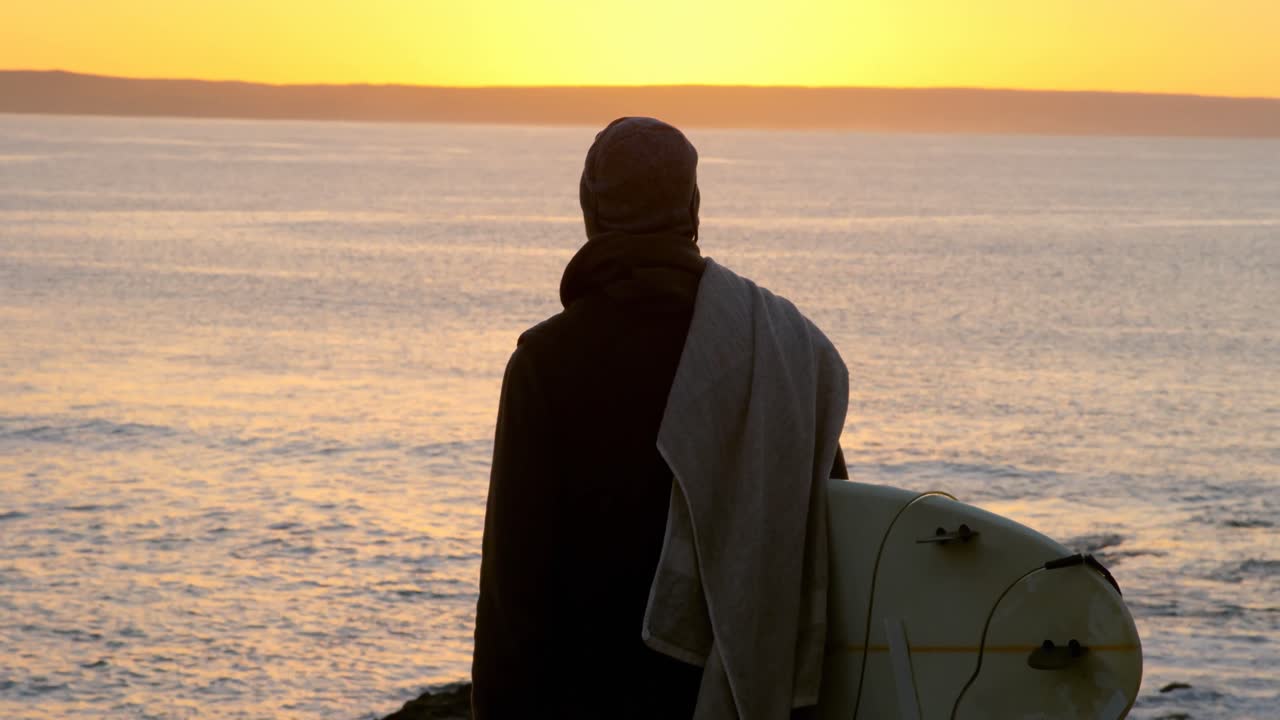 바 ⁇ 가 근처에 서있는 서프보드와 함께 중간 성인 남자의 뒷면 4k