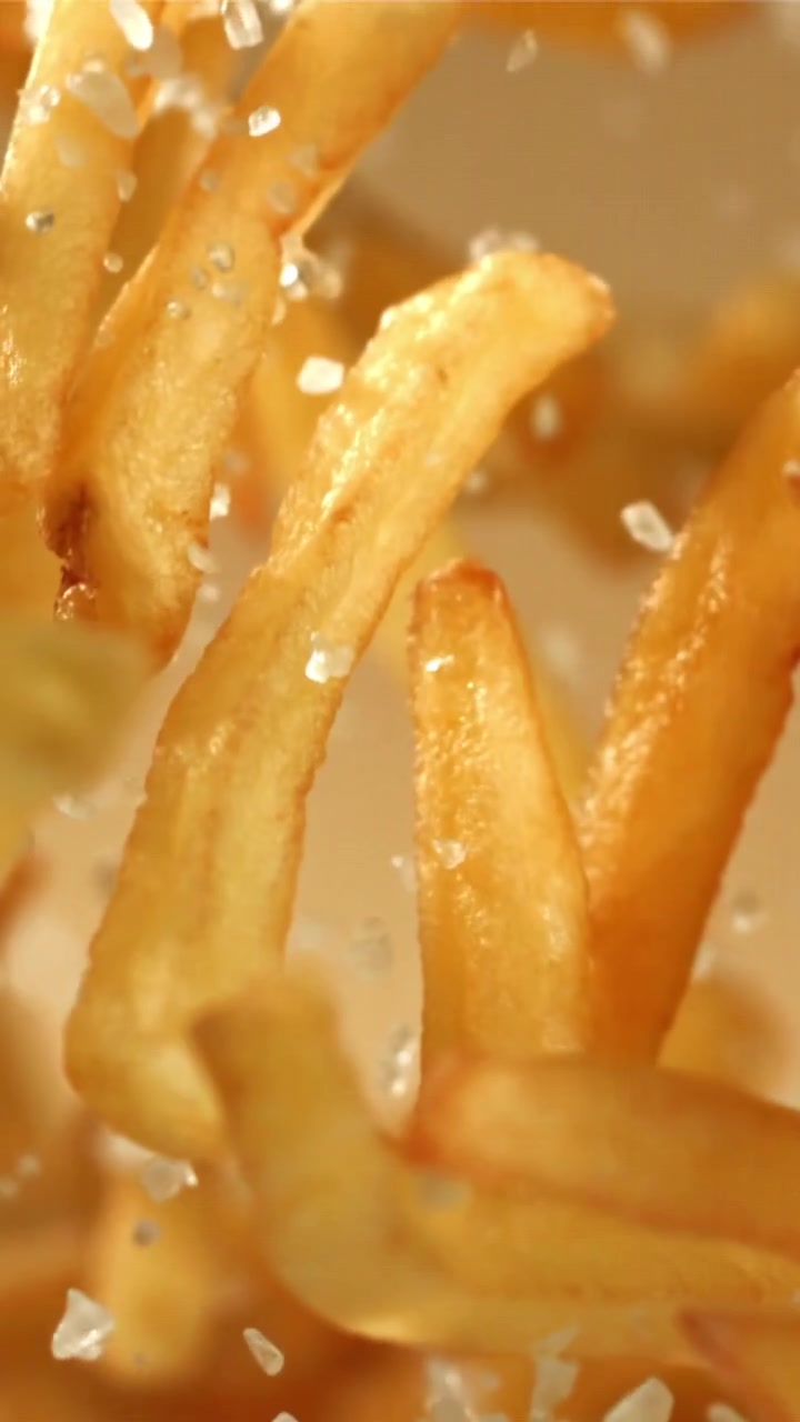 Patatine fritte dorate e croccanti che vengono salate al rallentatore