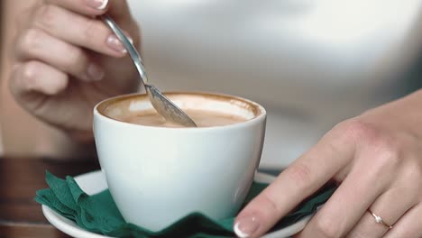 Mädchen-Rührt-Kaffee-Mit-Einem-Löffel-Um,-Während-In-Einem-Café-Löffel-Kaffeetropfen-In-Eine-Tasse-Fallen-Lassen,-Nahaufnahme-In-Zeitlupe