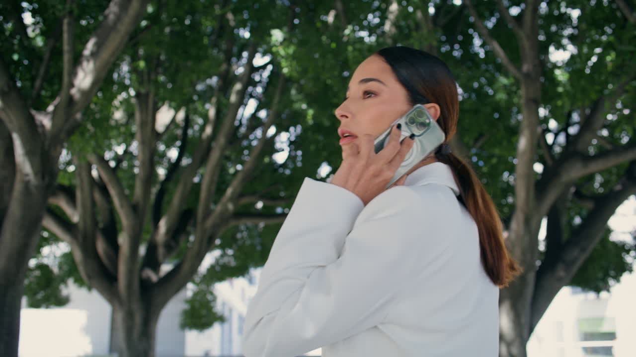 전화를 걸고 있는 사업가 여성. 가까이서 주변을 둘러보고 있는 여성. 말을 하는 여성.