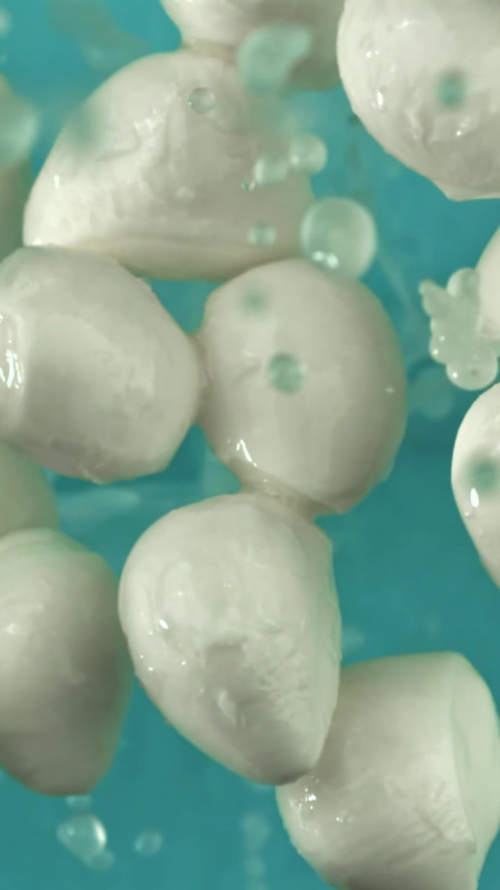 Schizzi d'acqua al rallentatore su palline di mozzarella bianca