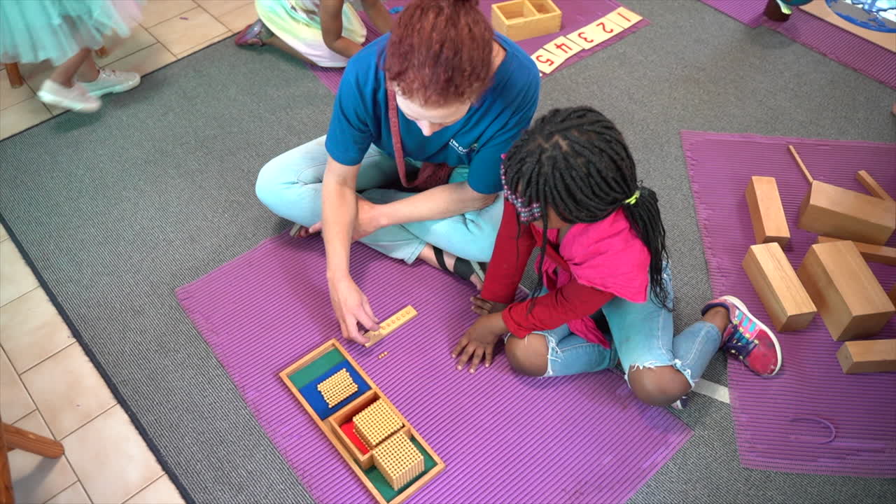 Guru mengajar anak di lantai di Sekolah Montessori Afrika Selatan