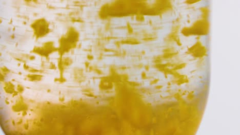 close-up view of yellow particles forming and settling in a clear liquid solution.