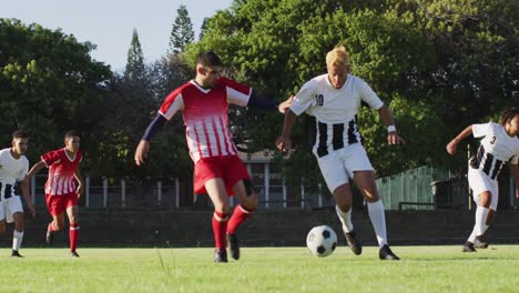 Video-Einer-Vielfältigen-Gruppe-Männlicher-Fußballspieler-Auf-Dem-Feld,-Die-Fußball-Spielen