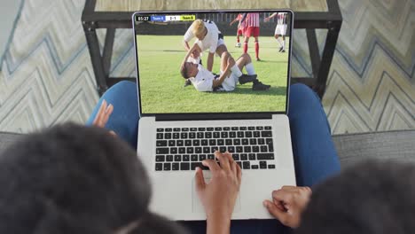 Video-De-Una-Pareja-Afroamericana-Sentada-En-Un-Sofá-Y-Viendo-Fútbol-En-Una-Computadora-Portátil-En-Casa