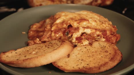 lasagna italiana rústica recién cocinada con rebanadas de pan de ajo