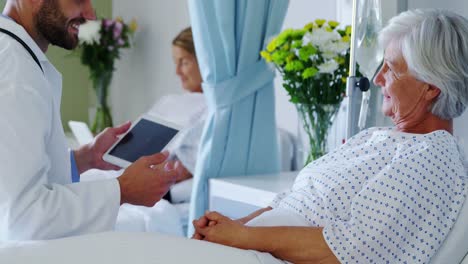 male doctor discussing medical report with senior woman on digital tablet