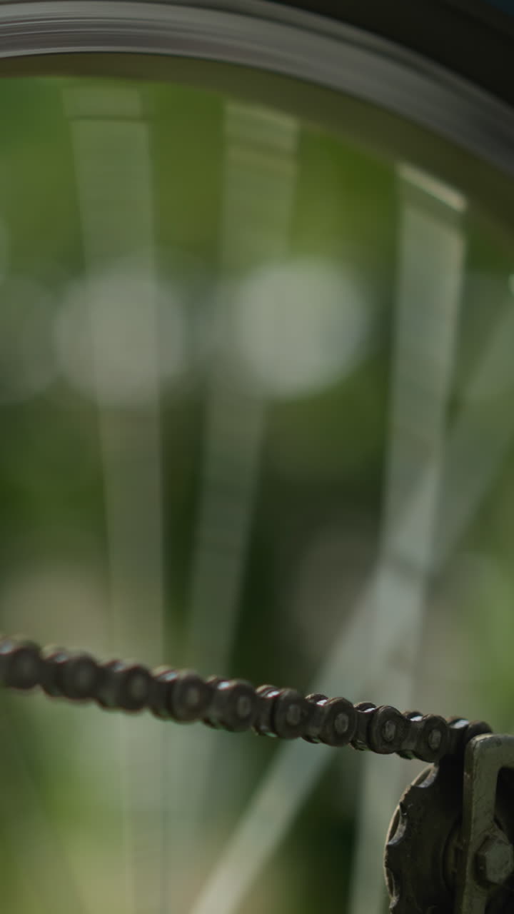 primer plano de la rueda trasera de la bicicleta y el sistema de engranajes mientras la cadena gira rápidamente antes de detenerse gradualmente, el enfoque está en la cadena y los radios, con el fondo borroso por el movimiento