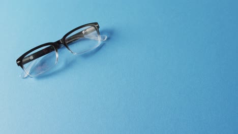 video of pair of glasses on blue background with copy space