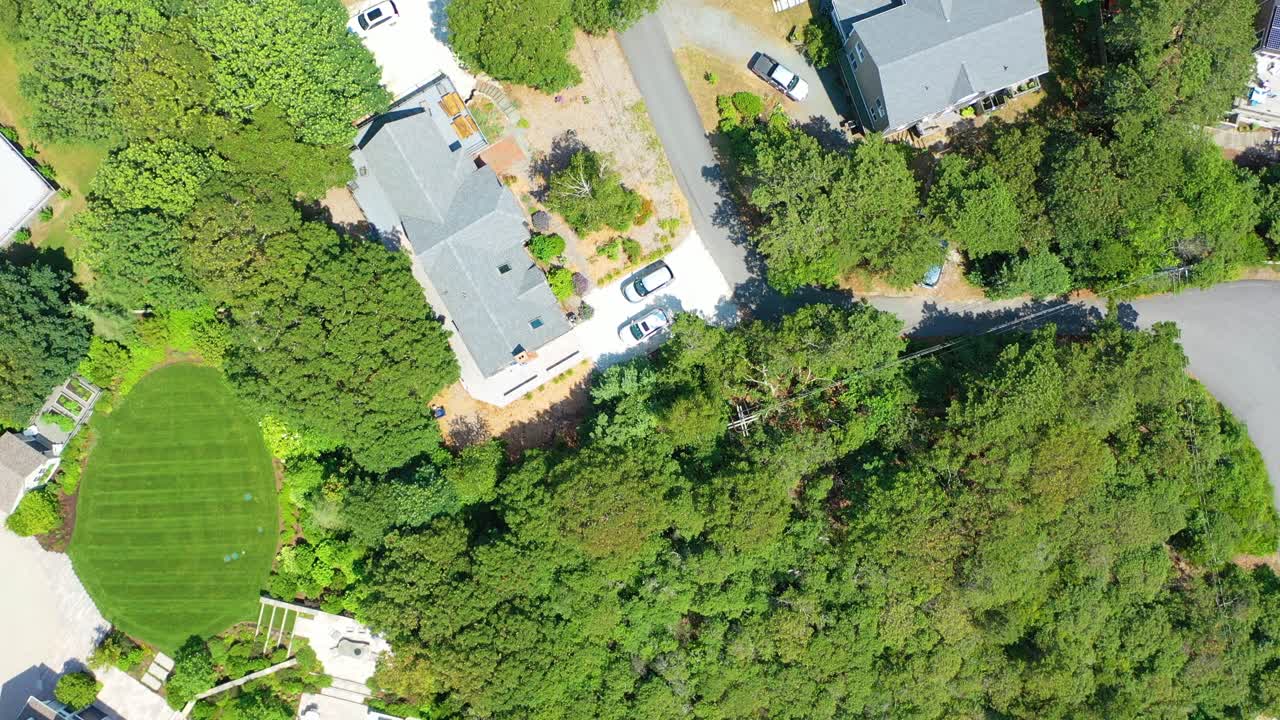 Cape Cod aerial footage shows beach houses nestled among trees, sandy pathways to the shore, and families enjoying the golden beach beside glistening ocean waters