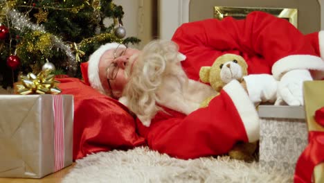 papá noel durmiendo con regalos de navidad y un oso de peluche