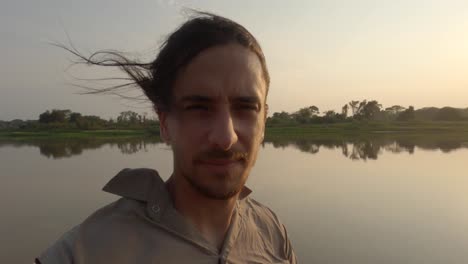 hombre mirando a su alrededor mientras está en barco por el río con el sol brillando