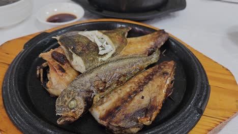 Person-Eating-Grilled-Fish-Using-Chopsticks-At-a-Korean-Restaurant-In-Sokcho,-South-Korea