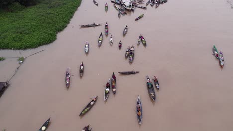 Drone-flies-over-Sungai-Martapura-river-full-of-wooden-boats-full-food-at-floating-market,-aerial