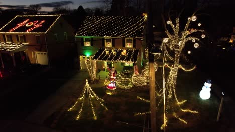 drone christmas lights house pan right to left around traffic light at dusk with festive lights on