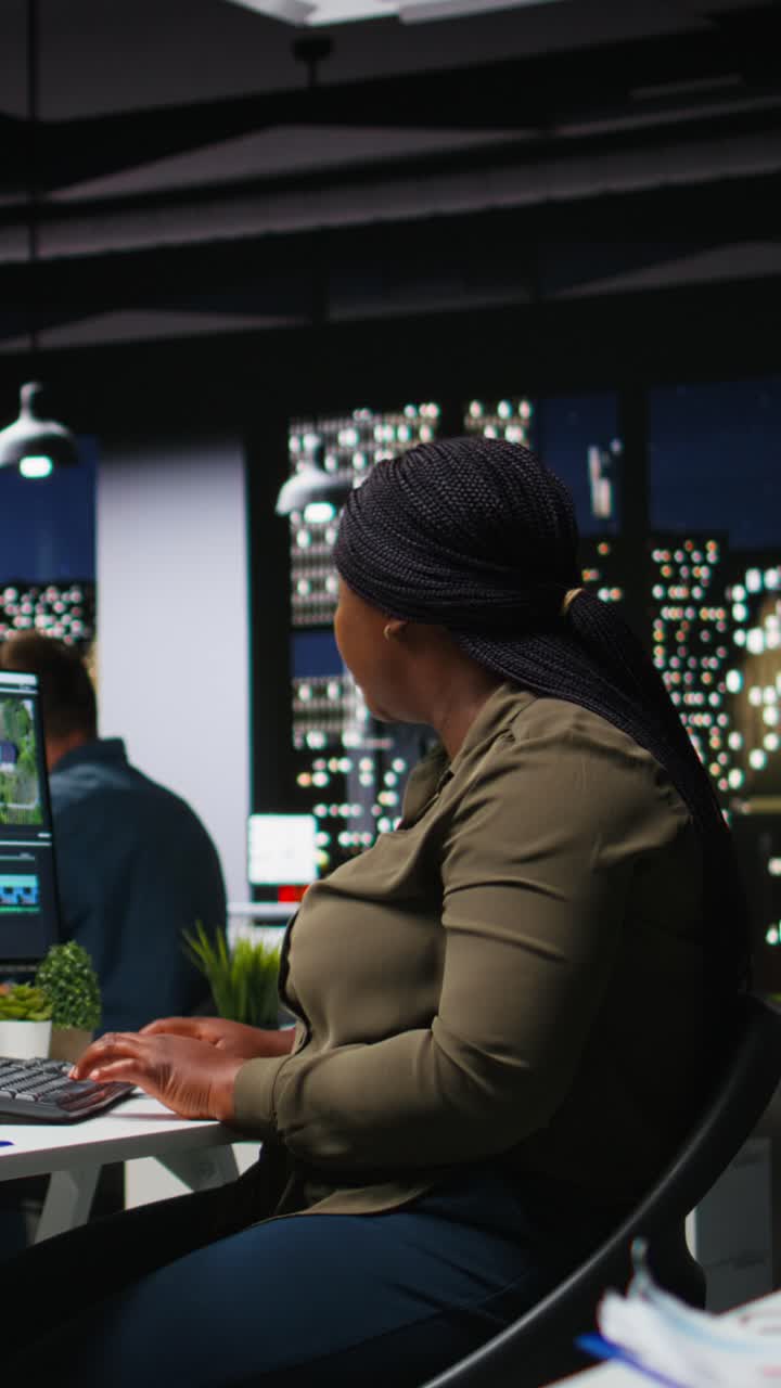 Vertical Video African american female editor working with dual monitors in creative office