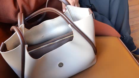 woman opening a white leather handbag