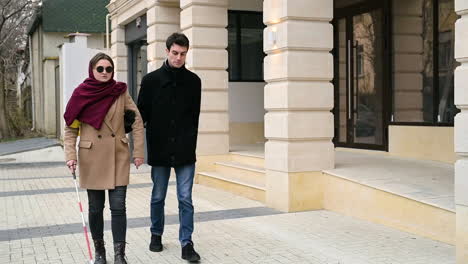 Vista-Frontal-De-Un-Hombre-Y-Una-Mujer-Ciega-Caminando-En-La-Calle