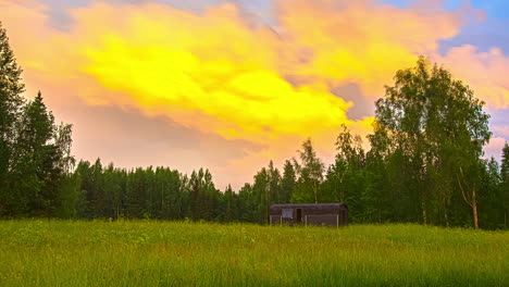 thermowood cabin in beautiful green landscape and forest in background - colorful flying clouds at sky during sunset - 5k timelapse shot