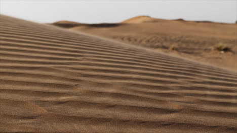 Arena-En-Cámara-Lenta-Que-Sopla-A-Través-Del-Desierto-En-El-Paisaje-Del-Desierto-Del-Medio-Oriente,-Dunas-De-Arena-En-Los-Emiratos-árabes-Unidos-Cerca-De-Dubai