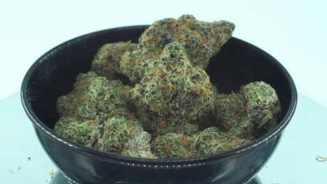 Close-up-shot-of-a-Marijuana-sativa-Super-Lemon-Amnesia-Haze-rock-flowers,-yellow,-green-and-purple-Kush,-on-a-reflecting-360-rotating-stand,-in-a-black-shiny-bowl,-Slow-motion-4K-video