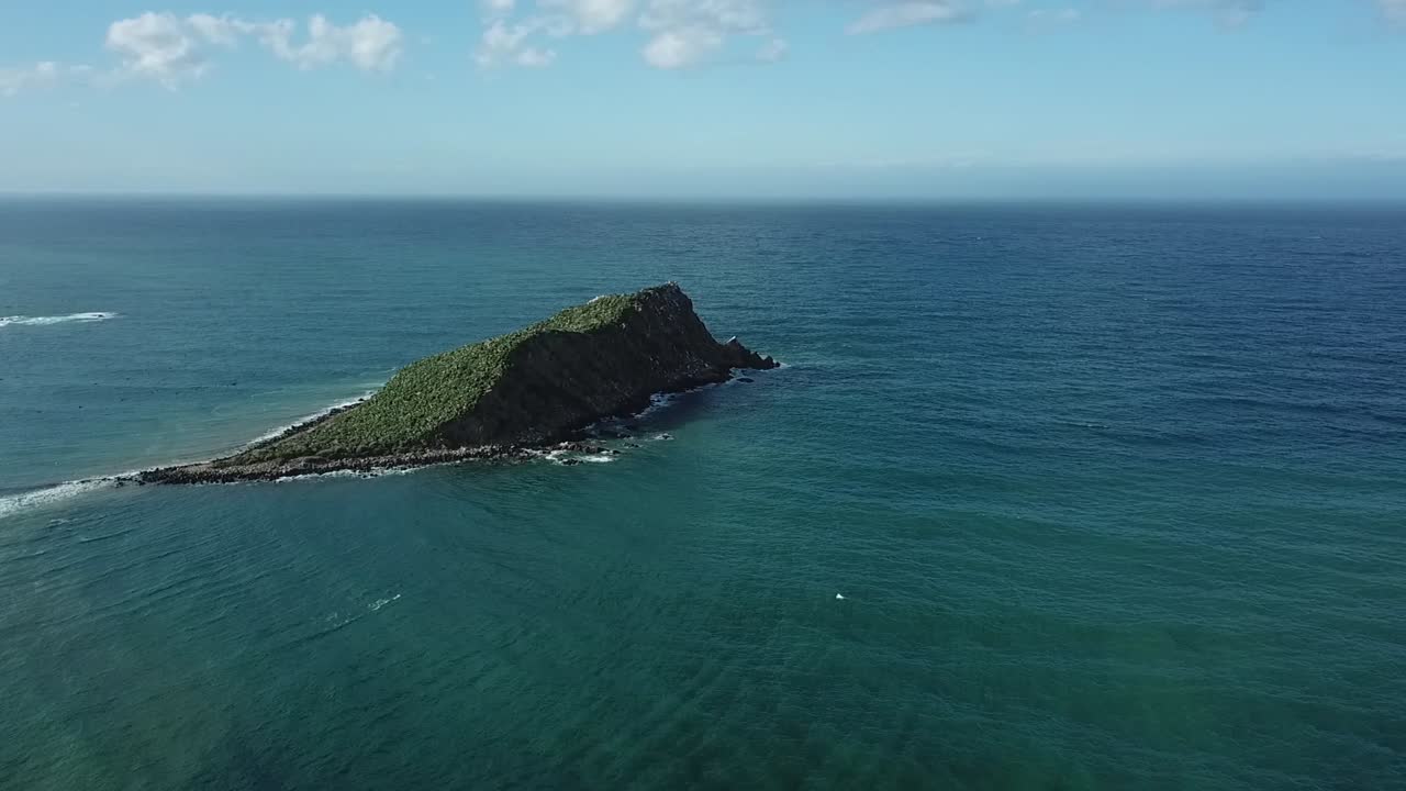Stunning summer view of a solitary rock islet sitting in transparent turquoise water near the beach. A perfect Mediterranean vacation scene