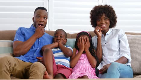 Family-sitting-on-sofa-and-watching-television