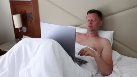 man using a laptop in bed