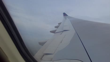 a través de la ventana del avión vista del ala del avión con aletas abriendo y volando a través de hermosas nubes