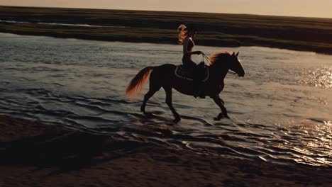 cowgirl riding horse in a river at sunset