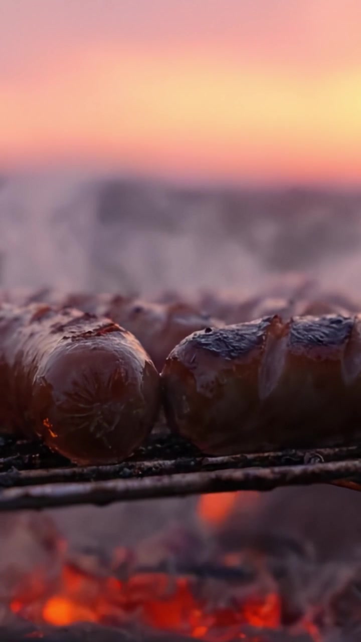 Grigliare salsicce succulente su una fiamma ardente al tramonto, catturando l'essenza della cucina all'aperto e il piacere di un pasto cucinato alla perfezione.