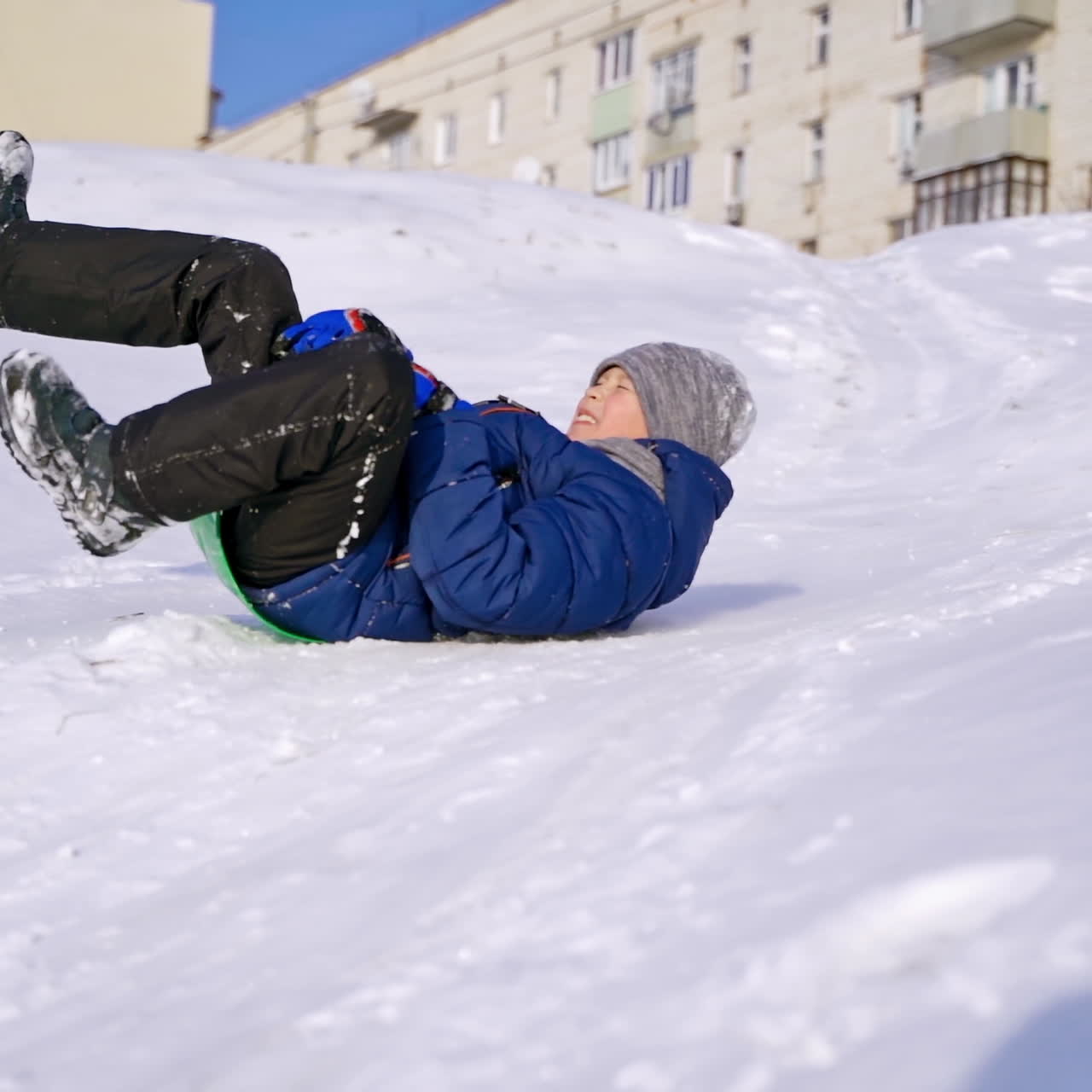 Frost winter season. Ride down the hills, winter games and fun. Kid laughing, sledging down a hill. Child rides down a hill, winter games and fun. Slow motion.