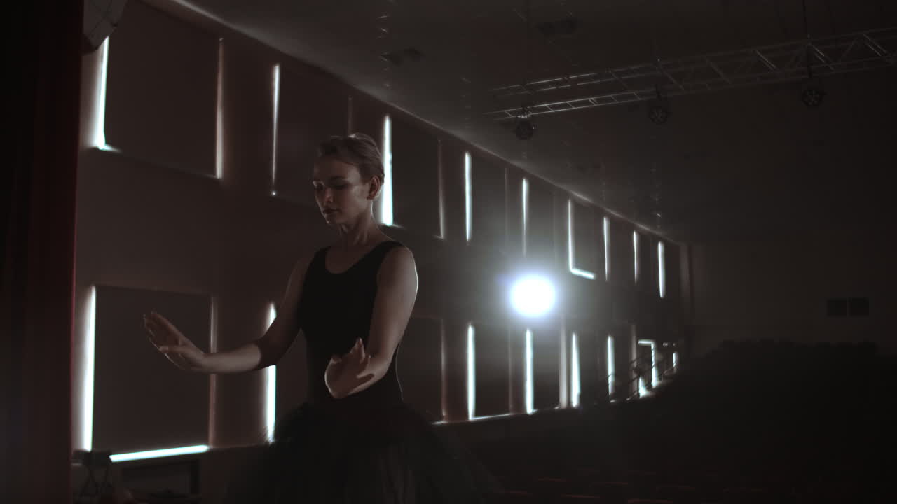 movimiento lento: diligente joven bailarina graciosa bailando elementos de ballet clásico en la oscuridad con luz y humo en el fondo. hermosa joven bailarín en la oscuridade.