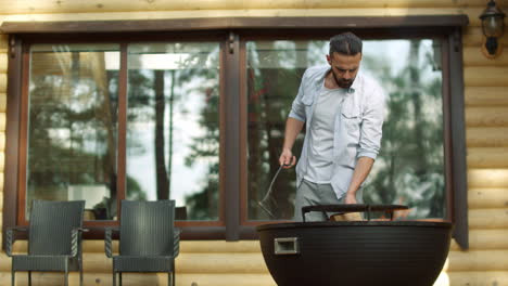 Chico-Concentrado-Usando-Póquer-Al-Aire-Libre.-Hombre-Chef-Cocinando-Comida-En-La-Parrilla-Cerca-De-La-Casa.