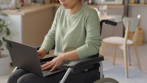 woman using laptop in wheelchair at home