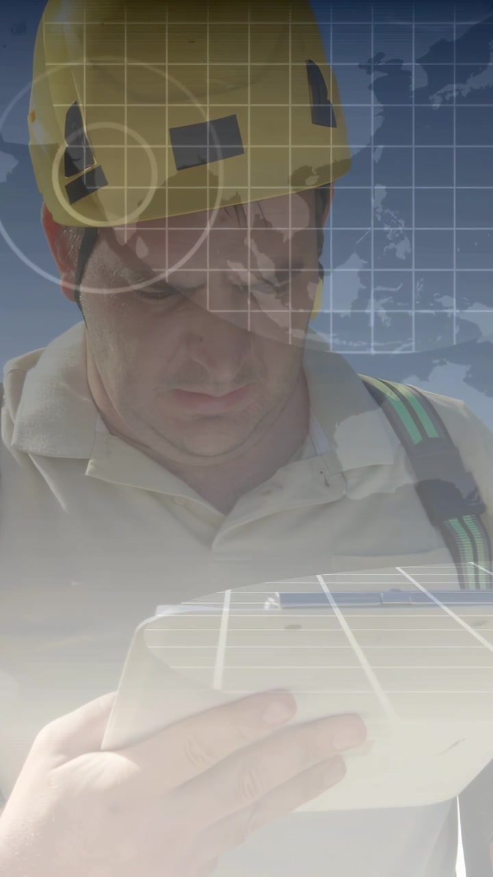 Vertical video: Male worker raising tablet, activating tech HUD grid over helmet, checking map data