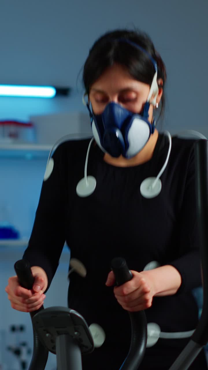 Woman undergoing a physiological exercise test with sensors and a mask