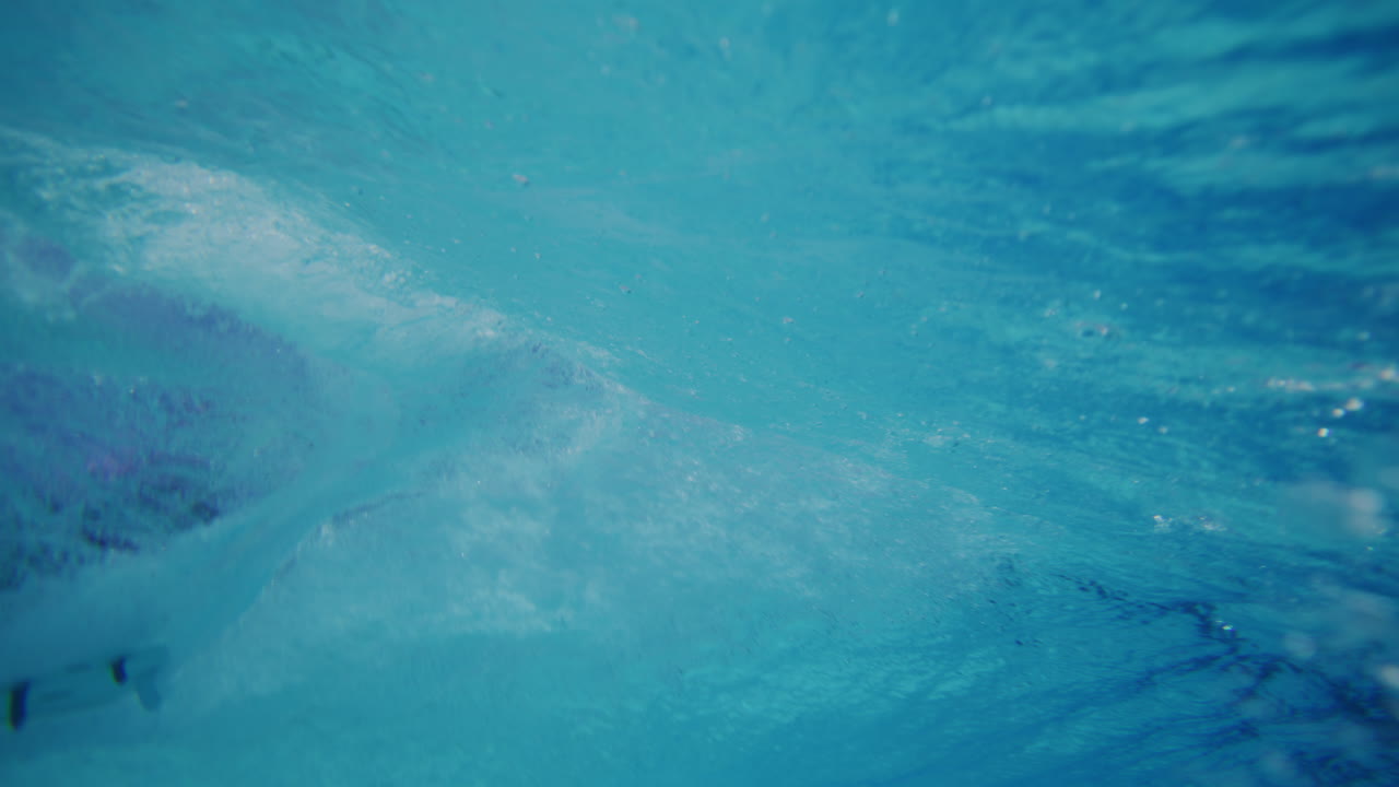 Slow motion underwater scene of light beams dancing across wave pool bottom