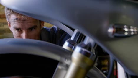 male mechanic repairing motorbike in repair garage 4k