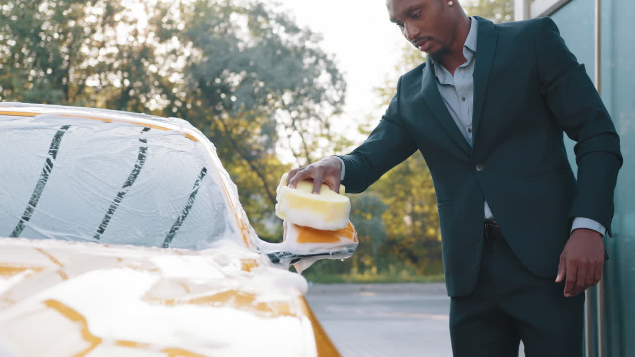 남자가 야외 세탁소에서 노란색 차를 고 있다