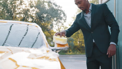 man washing a yellow car at an outdoor car wash