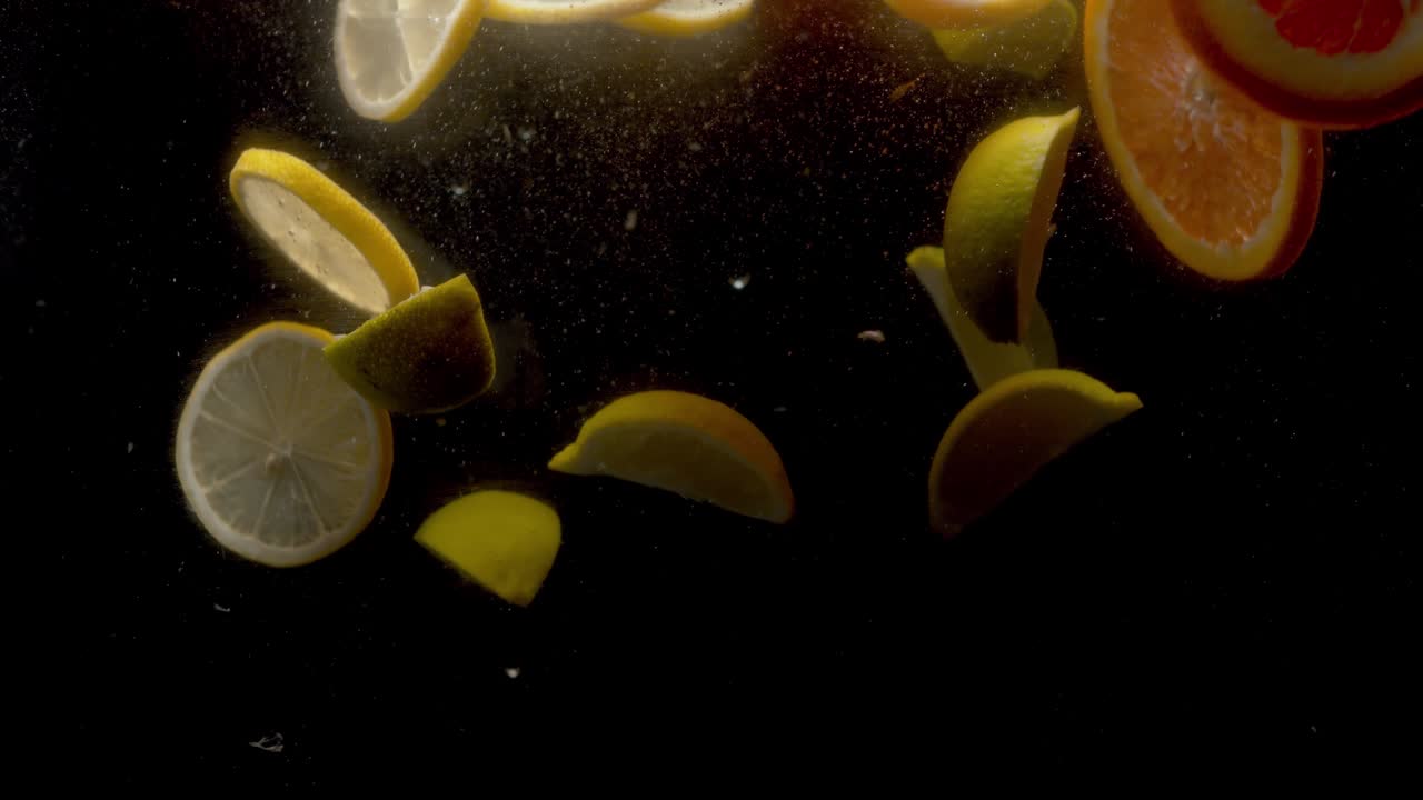 limones cortados y naranjas cayendo en el agua