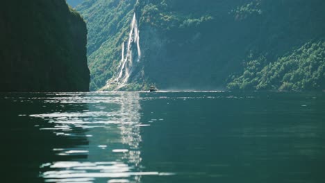 a motorboat glides through the calm waters of geiranger fjord, with the majestic seven sisters waterfall in the background