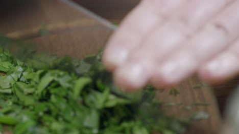 Close-up-view-of-chef-cutting-fresh-parsley-for-chimichurri,-with-kitchen-ax-knife-on-wooden-board